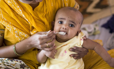 A mother feeding the baby with spoon